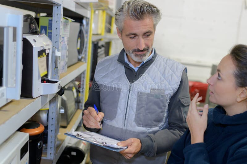 Manager showing clipboard to worker in warehouse royalty free stock photos