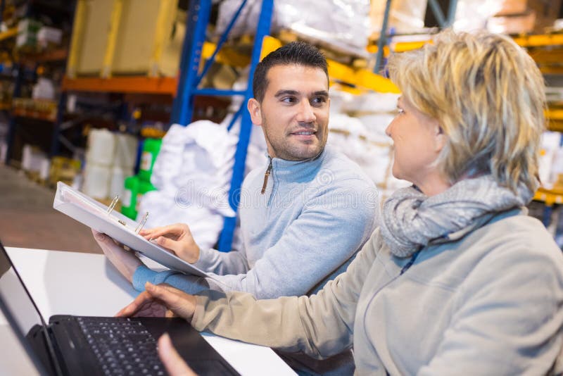 Manager showing clipboard to worker in warehouse royalty free stock photography