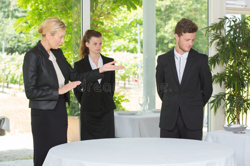 Manager showing younger cheerful colleagues how to work stock images
