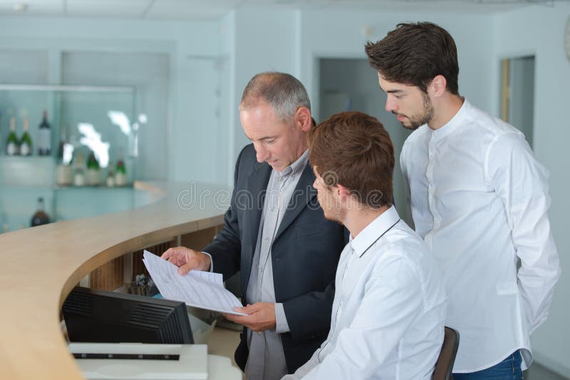 Manager showing paperwork to hotel reception staff stock photography