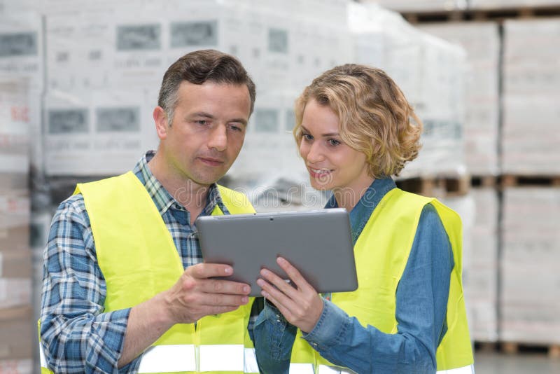 Manager showing tablet to worker in warehouse stock photos