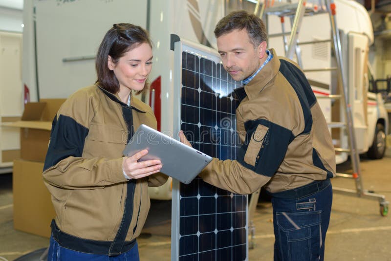 Manager showing tablet to worker in warehouse stock image