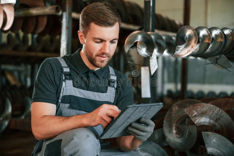 Manager is using digital tablet. Man in uniform is in workstation developing details of agriculture technique royalty free stock photos
