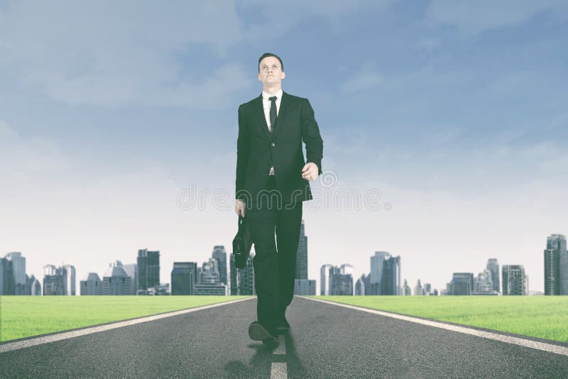 Manager walking on the road with city background stock photo Manager walking on the road with city background stock photo