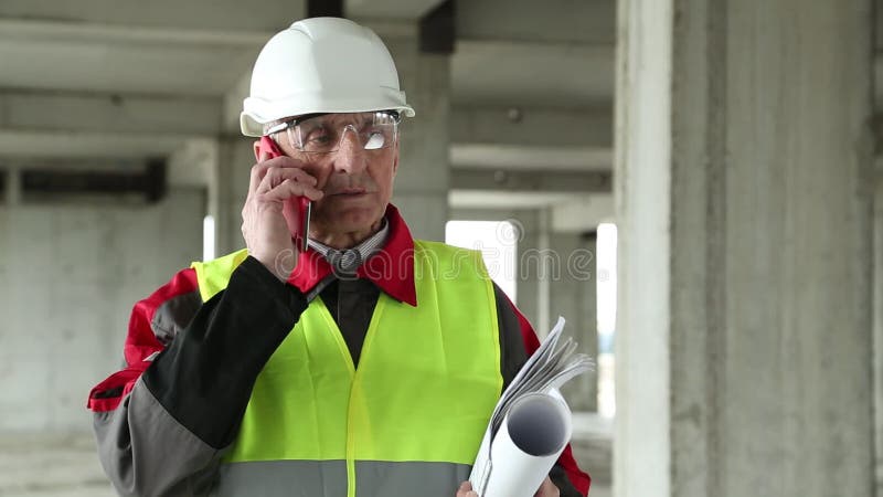 Manager of the works with red smartphone on the construction site