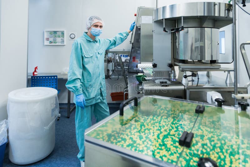 Manarbetare för farmaceutisk bransch i skyddskläderfungerande produktion av minnestavlor i sterila arbetsförhållanden arkivfoton Manarbetare för farmaceutisk bransch i skyddskläderfungerande produktion av minnestavlor i sterila arbetsförhållanden arkivfoton