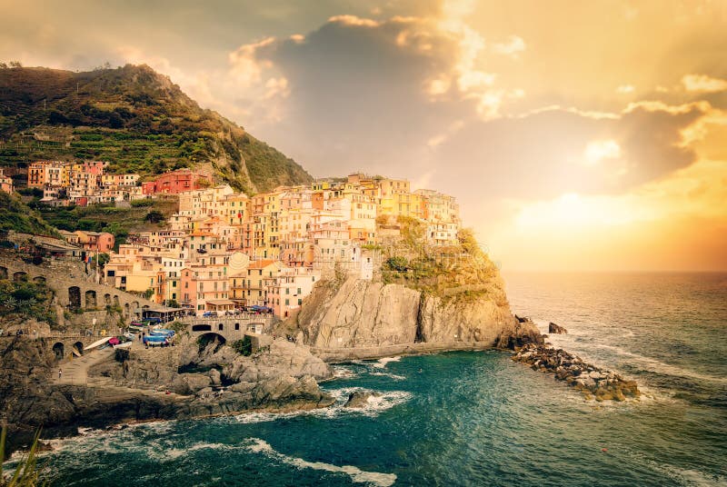 Manarola, Cinque Terre, Ιταλία Ζωηρόχρωμα παραδοσιακά σπίτια σε έναν βράχο πέρα από τη Μεσόγειο στο δραματικό ηλιοβασίλεμα στοκ εικόνες