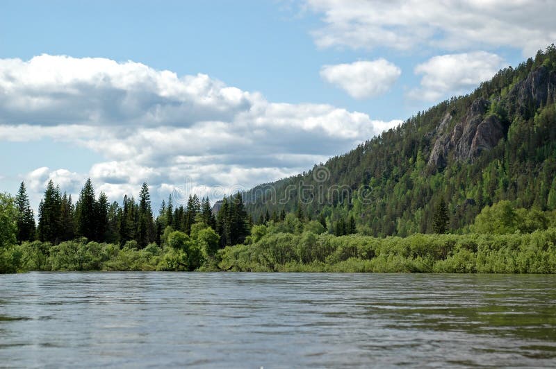 Magnificent landscape. The Siberian mountain river Mana against a mountain taiga, rocks and the sky. Magnificent landscape. The Siberian mountain river Mana against a mountain taiga, rocks and the sky.