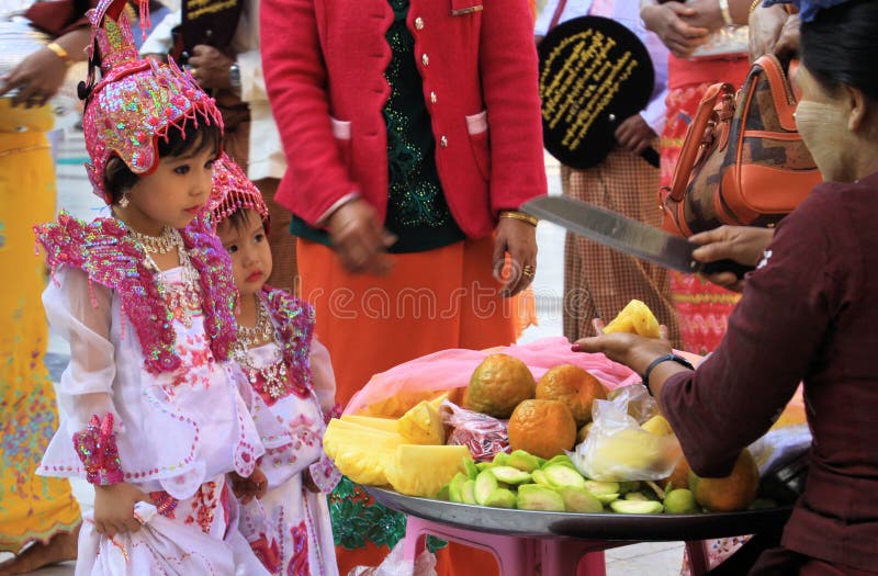 MANDALAY, MYANMAR - 18 DE DICIEMBRE 2015: Muchacha birmana linda que elige las frutas durante ceremonia en Maha Muni Pagoda imagen de archivo libre de regalías MANDALAY, MYANMAR - 18 DE DICIEMBRE 2015: Muchacha birmana linda que elige las frutas durante ceremonia en Maha Muni Pagoda imagen de archivo libre de regalías