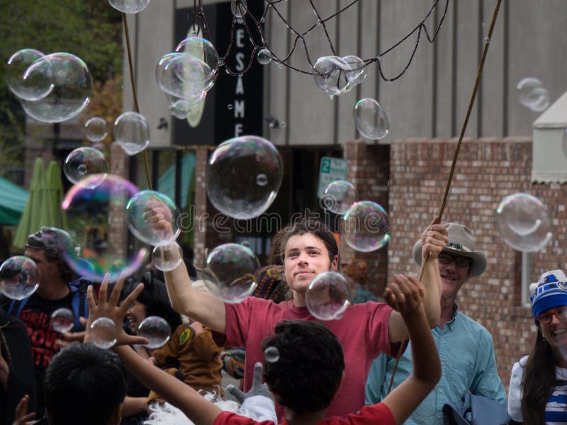 A young man makes a multitude of large soap bubbles for a happy crowd and excited children at a Fourth of July street party in Ashland Oregon. A young man makes a multitude of large soap bubbles for a happy crowd and excited children at a Fourth of July street party in Ashland Oregon.