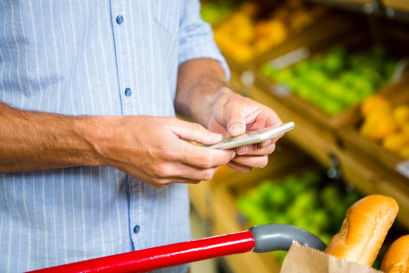 Mandare un sms dell'uomo ed acquisto di drogheria immagini stock libere da diritti Mandare un sms dell'uomo ed acquisto di drogheria immagini stock libere da diritti