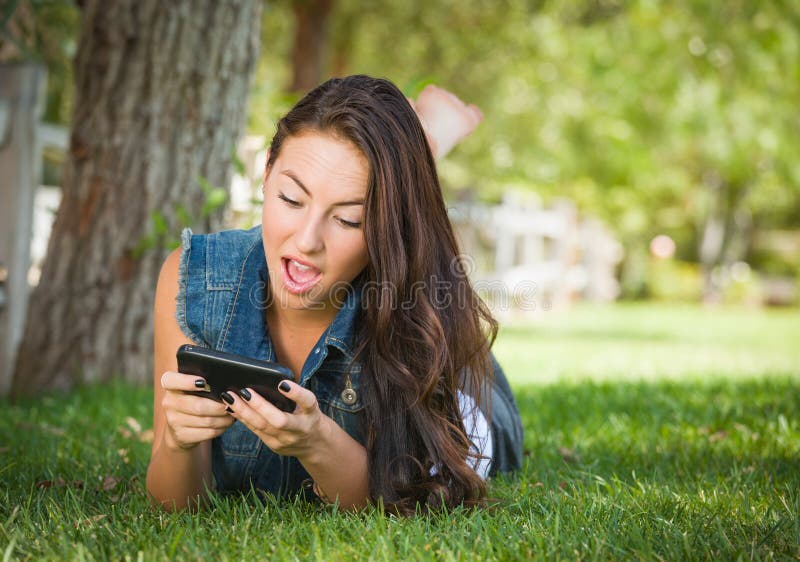 Mandare un sms femminile teenager colpito della corsa mista sul suo Smart Phone fotografie stock Mandare un sms femminile teenager colpito della corsa mista sul suo Smart Phone fotografie stock