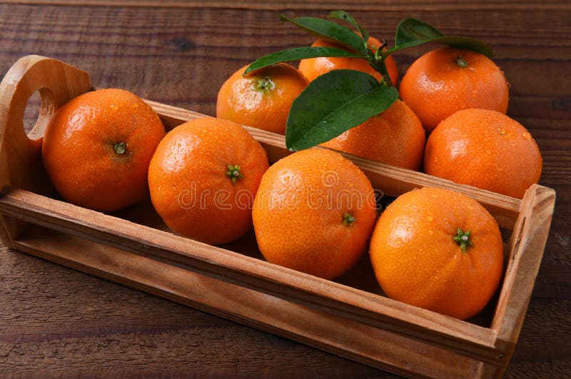 Closeup of a small crate of Mandarin Oranges on a rustic wood table. Closeup of a small crate of Mandarin Oranges on a rustic wood table.