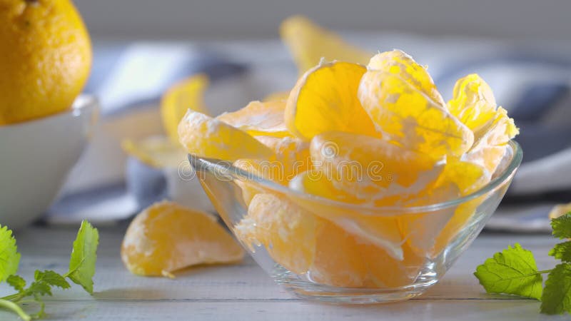 Mandarinas frescas maduras con hierbas melissa en tazón de vidrio sobre mesa de madera Captura de vídeo de 4.000 fps