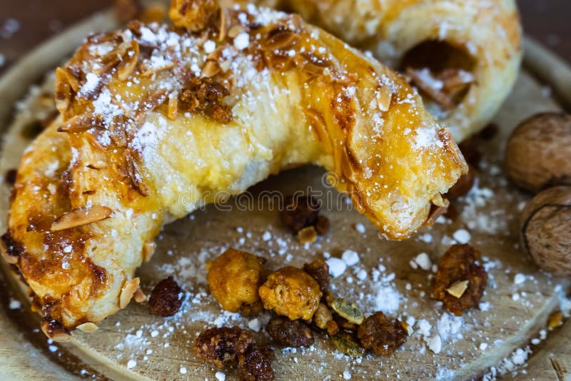 Mandelhörnchen mit Puderzucker und Nüssen auf einem hölzernen Brett lizenzfreies stockfoto Mandelhörnchen mit Puderzucker und Nüssen auf einem hölzernen Brett lizenzfreies stockfoto