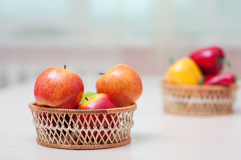 Baskets with ripe red apples, and bell pepper on table against the window. Baskets with ripe red apples, and bell pepper on table against the window.