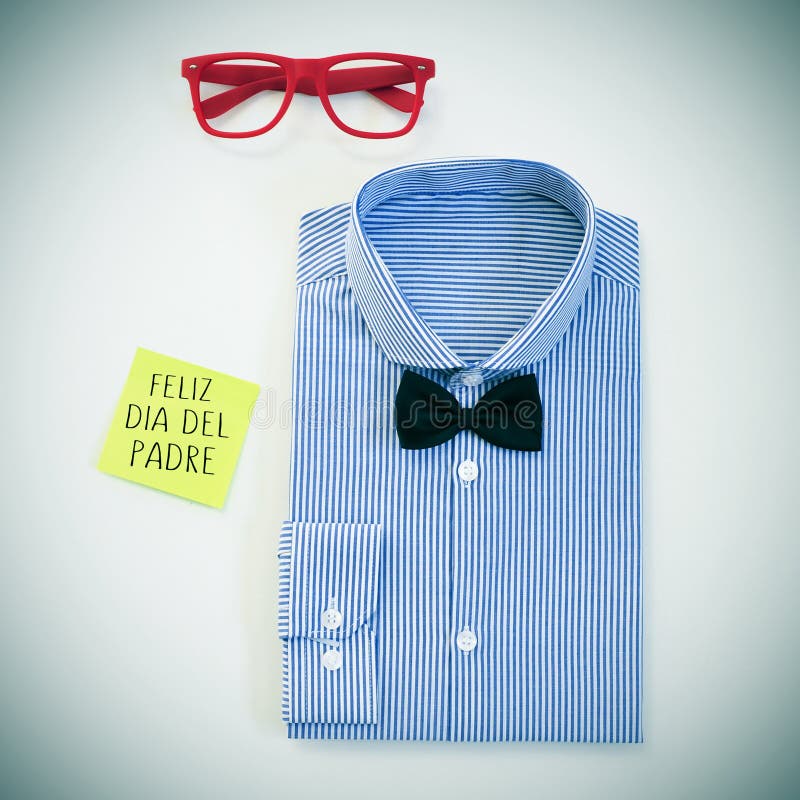 High-angle shot of a table with a pair of eyeglasses, a bow tie and a shirt, and a sticky note with the text feliz dia del padre, happy fathers day in spanish written in it. High-angle shot of a table with a pair of eyeglasses, a bow tie and a shirt, and a sticky note with the text feliz dia del padre, happy fathers day in spanish written in it