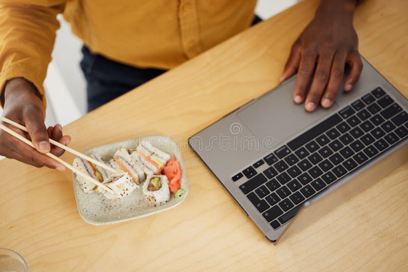 Maneggia il business man e il sushi con il laptop scorrevole e mangiando alla vista superiore della scrivania e ricercando in uffi fotografia stock libera da diritti