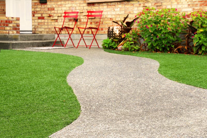 Maneira da caminhada com a grama perfeita que ajardina com grama artificial na área residencial foto de stock Maneira da caminhada com a grama perfeita que ajardina com grama artificial na área residencial foto de stock