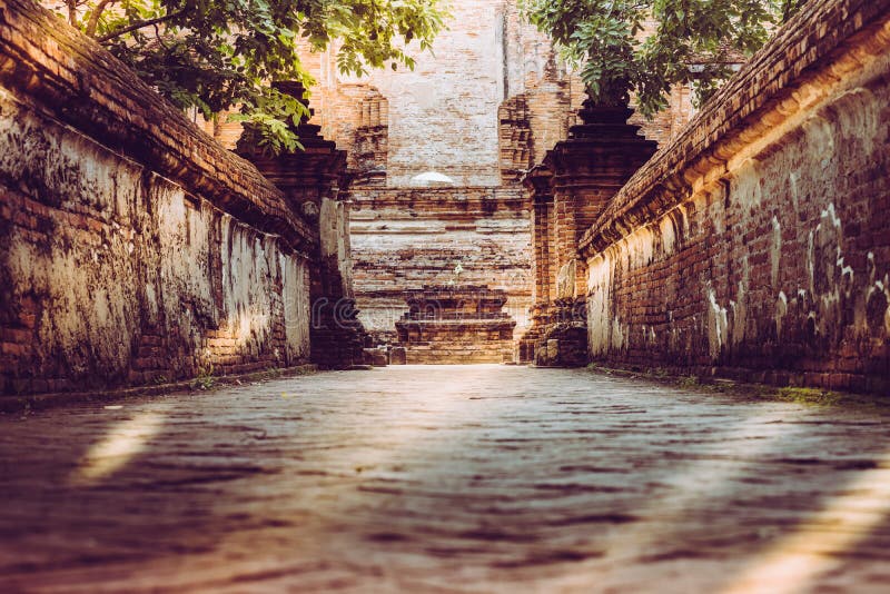 Walk way or entered to old chapel and pagoda with red brick wall of Wat Maheyong temple , Ayutthaya historical park Thailand. Vintage photo effect. Walk way or entered to old chapel and pagoda with red brick wall of Wat Maheyong temple , Ayutthaya historical park Thailand. Vintage photo effect.