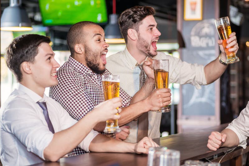 Manfans som skriker och håller ögonen på fotboll på TV- och drinköl T arkivbilder Manfans som skriker och håller ögonen på fotboll på TV- och drinköl T arkivbilder