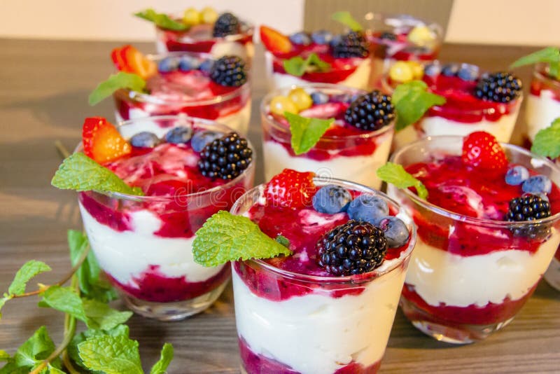 Mangiando yogurt con la fragola, i mirtilli, la menta, il granola, il gelso in ciotole di vetro, l'alimento sano ed al il concett immagini stock libere da diritti Mangiando yogurt con la fragola, i mirtilli, la menta, il granola, il gelso in ciotole di vetro, l'alimento sano ed al il concett immagini stock libere da diritti