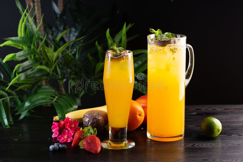 Mangolimonade - passievrucht in een kruik en een glas en fruit op een houten achtergrond stock foto Mangolimonade - passievrucht in een kruik en een glas en fruit op een houten achtergrond stock foto