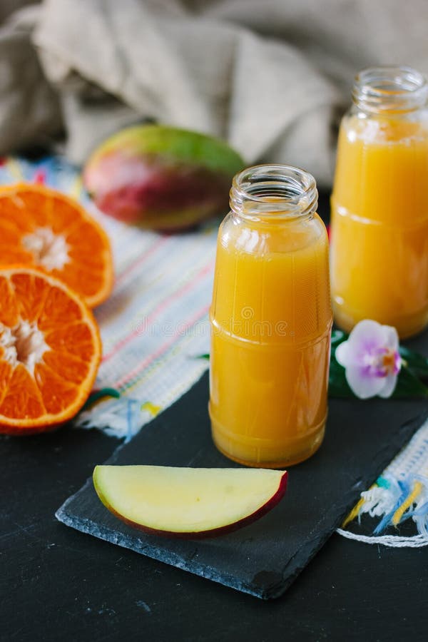 Mangue et smoothie orange dans la bouteille transparente photo libre de droits Mangue et smoothie orange dans la bouteille transparente photo libre de droits