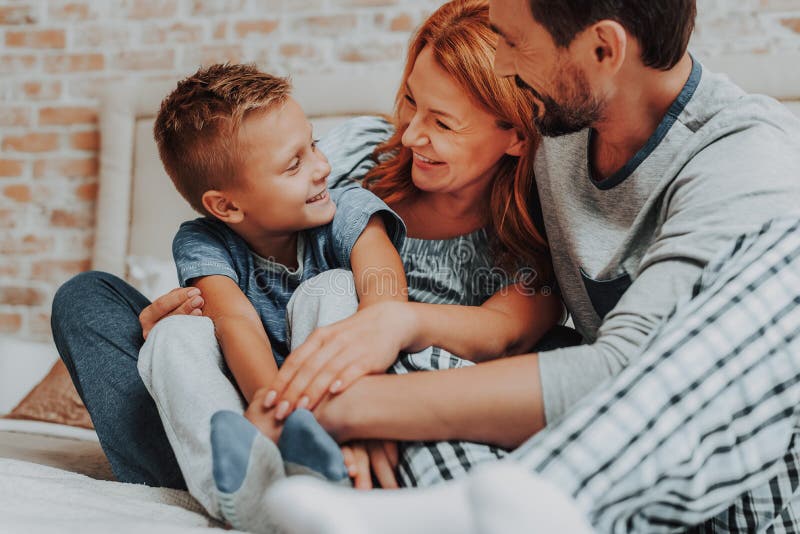 Manhã feliz com família de sorriso junto na cama imagem de stock Manhã feliz com família de sorriso junto na cama imagem de stock