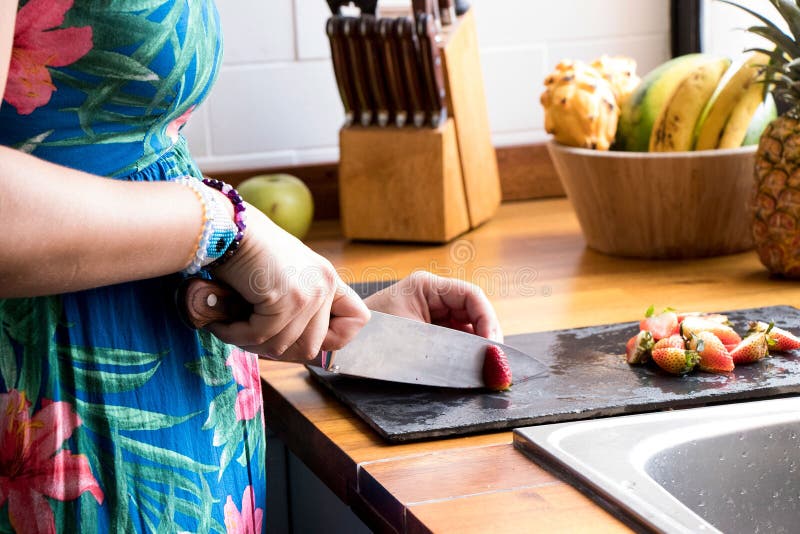 Mani che tagliano con le fragole rosse di un coltello immagini stock Mani che tagliano con le fragole rosse di un coltello immagini stock