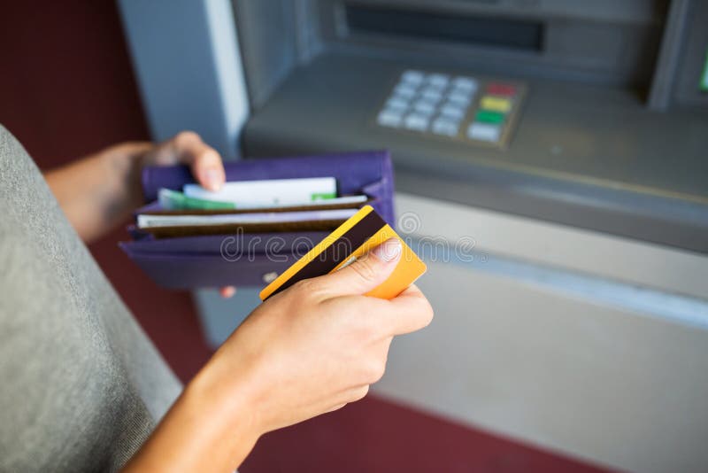 Mani con la carta di credito e dei soldi alla macchina di bancomat
