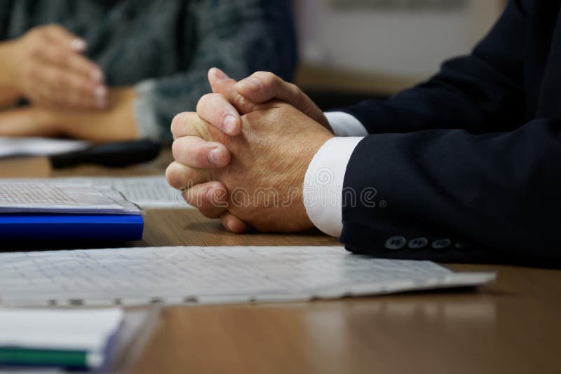 Hands of the boss during a meeting and adjudication. Clenched fingers. Teamwork. Shallow depth of field. Hands of the boss during a meeting and adjudication. Clenched fingers. Teamwork. Shallow depth of field