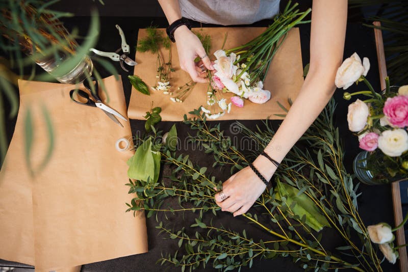 Mani del fiorista della donna che creano il mazzo del fiore sulla tavola fotografie stock libere da diritti Mani del fiorista della donna che creano il mazzo del fiore sulla tavola fotografie stock libere da diritti