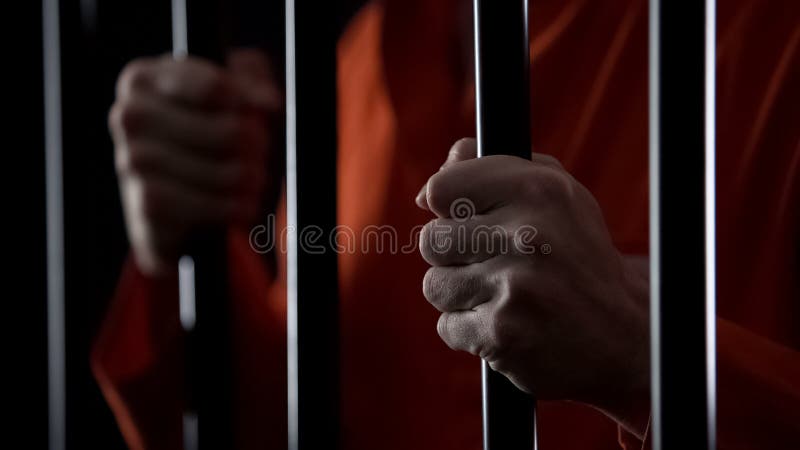 Mani del maschio arrestato disperato che tiene le barre della prigione, giudizio ingiusto, fine su
