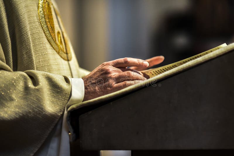Mani del prete cattolico che leggono una bibbia