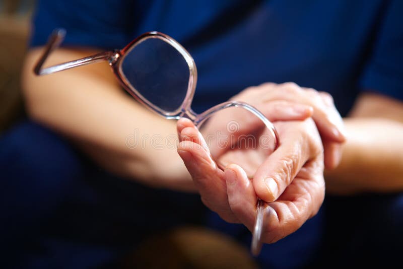 Mani della donna anziana con gli occhiali fotografia stock Mani della donna anziana con gli occhiali fotografia stock