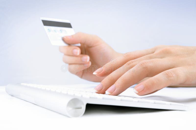 Mani della donna che tengono la carta di credito e digitare fotografia stock Mani della donna che tengono la carta di credito e digitare fotografia stock