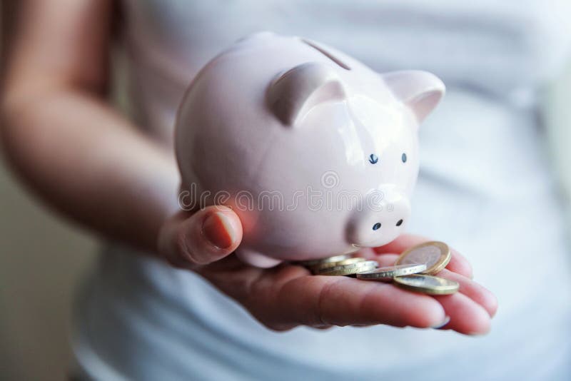 Mani della donna che tengono le monete rosa dell'euro e del porcellino salvadanaio fotografia stock libera da diritti Mani della donna che tengono le monete rosa dell'euro e del porcellino salvadanaio fotografia stock libera da diritti