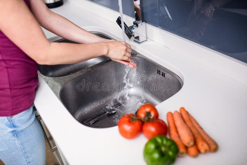 Mani di lavaggio della donna al dispersore di cucina fotografie stock libere da diritti Mani di lavaggio della donna al dispersore di cucina fotografie stock libere da diritti