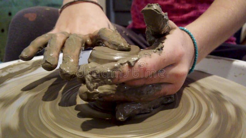 Mani di un bambino che lavora su una ruota di ceramica per preparare un vaso di argilla