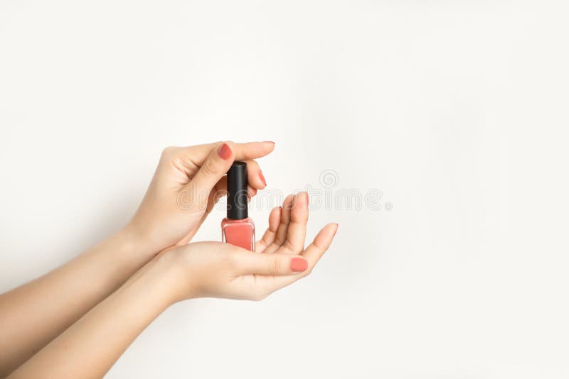 Mani di una donna con il manicure e la bottiglia rosso scuro dello smalto immagine stock libera da diritti Mani di una donna con il manicure e la bottiglia rosso scuro dello smalto immagine stock libera da diritti