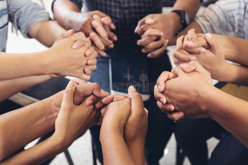 Mani diverse che stringono la mano attorno a voi per pregare Dio l'uno per l'altro e sostenere insieme il lavoro di squadra