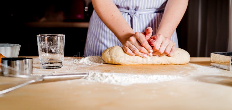 Mani femminili che producono pasta sulla tavola di legno fotografia stock Mani femminili che producono pasta sulla tavola di legno fotografia stock