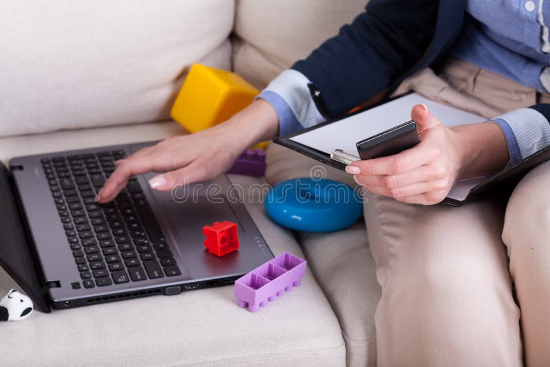 Mani femminili che scrivono sui giocattoli dei bambini e del computer portatile fotografie stock libere da diritti