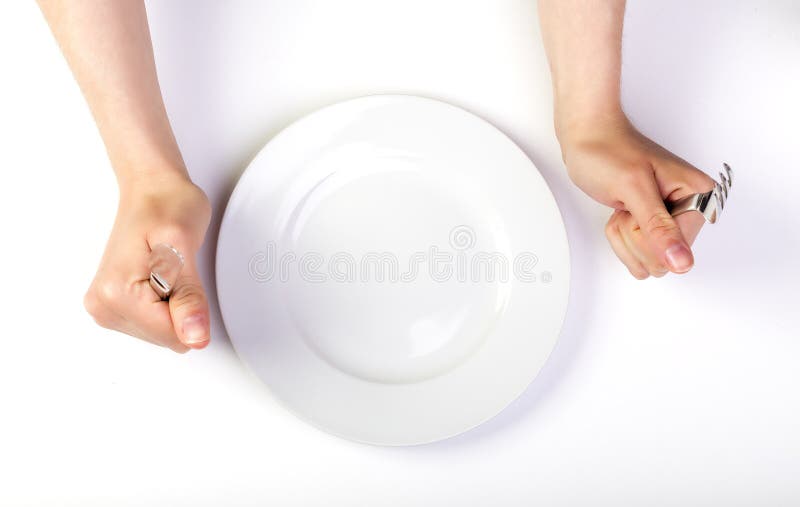Mani femminili che tengono forcella e coltello accanto ad un piatto vuoto immagini stock Mani femminili che tengono forcella e coltello accanto ad un piatto vuoto immagini stock