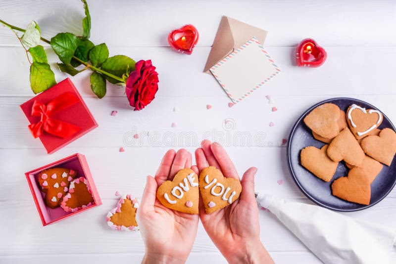 Mani femminili che tengono i biscotti casalinghi nella forma di cuore con amore voi parole come regalo per l'amante il giorno del fotografia stock libera da diritti