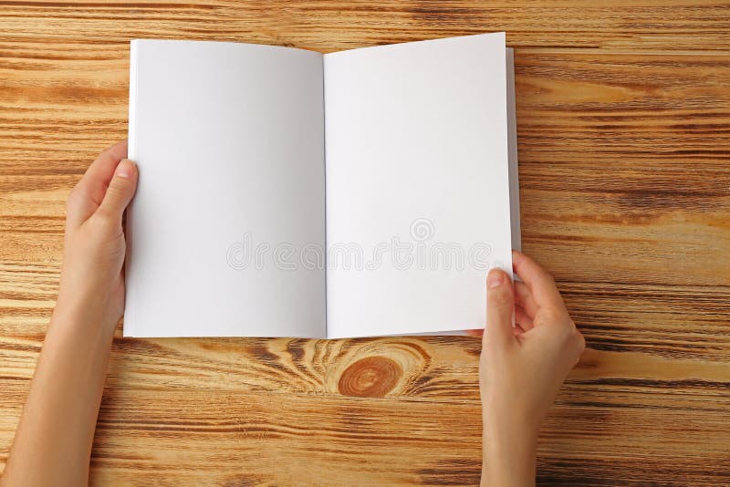 Mani femminili che tengono l'opuscolo aperto dello spazio in bianco fotografia stock Mani femminili che tengono l'opuscolo aperto dello spazio in bianco fotografia stock