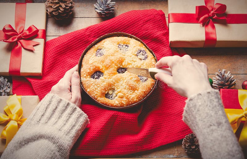 Mani femminili che tengono la torta di Natale con i regali intorno immagini stock Mani femminili che tengono la torta di Natale con i regali intorno immagini stock