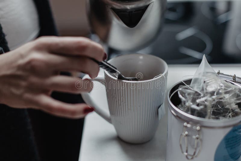 Mani femminili che versano acqua dal bollitore fotografia stock Mani femminili che versano acqua dal bollitore fotografia stock