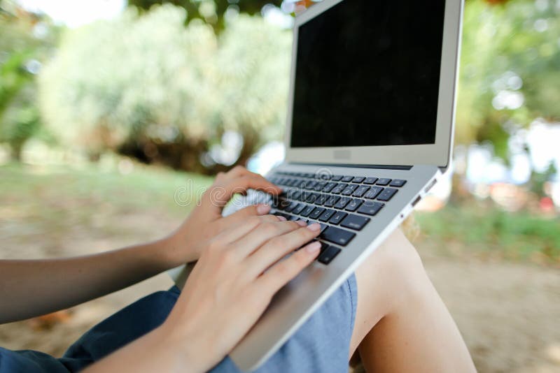 Mani gentili delle donne con laptop con sabbia sullo sfondo, schermo nero immagine stock